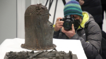 Ein Journalist dokumentiert Benin-Bronzen, die für die Rückgabe nach Nigeria im Ethnologischen Museum Dahlem zusammen gestellt wurden. Foto: Wolfgang Kumm/dpa