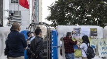 Der Demokratieaktivist Lee Cheuk-Yan hängt vor dem Liaison Office in Hongkong Schilder auf, um die in Shenzhen angeklagten Aktivisten zu unterstützen. Foto: epa/Miguel Candela