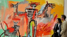 Besucher der Presse-Privatansicht der Ausstellung "Basquiat" betrachten das Gemälde "Junge und Hund in Jonnypump" (1982) im Museum der Fondation Beyeler in Riehen bei Basel. Foto: epa/Rolf Haid