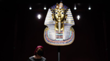 Eine Frau betrachtet eine Replik der Totenmaske in der Ausstellung «Tutanchamun - Sein Grab und die Schätze» im Museum Zeughaus. Foto: Uwe Anspach/dpa