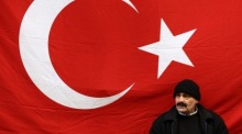 Alltag in Istanbul: Ein Mann sitzt nahe der Istiklal-Straße vor einer türkischen Flagge, während das Land politisch angespannt ist. Foto: EPA/Sedat Suna