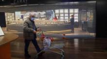 Ein mit einem Mundschutz maskierter Mann geht an einem geschlossenen Juweliergeschäft in einem Einkaufszentrum in Genf vorbei. Foto: epa/Salvatore Di Nolfi