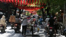 Eine Straßenhändlerin trägt Keramikwaren durch eine belebte Straße in Hanoi und bietet ihre Töpferarbeiten im Alltagsgeschäft zum Verkauf an. Foto: EPA/Luong Thai Linh