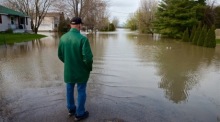 Ein evakuierter Mann steht vor überfluteter Straße, nachdem schwere Regenfälle zahlreiche Häuser und Gemeinden in Quebec getroffen haben. Foto: epa/Andre Pichette