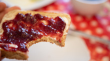 Ein Mann hält ein Toastbrot mit Himbeermarmelade in der Hand. Foto: Sebastian Gollnow/dpa