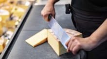 Eine Mitarbeiterin schneidet Käse Emmental. Neue US-Zölle belasten Exporte aus der Schweiz und weiter sorgen für Unsicherheit. Foto: epa/Til Buergy