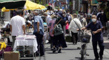 Leute schlendern durch Marktstände in einer Einkaufsstraße im Bezirk Sugamo in Tokio. Foto: epa/Franck Robichon