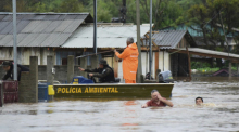 Polizeibeamte kontrollieren ein Haus, während Anwohner über eine überschwemmte Straße im Bundesstaat Rio Grande do Sul waten, nachdem ein Unwetter Überschwemmungen verursacht hat. Foto: Diogo Zanatta/Futura Press/ap/dpa