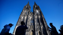 Touristen fotografieren den Kölner Dom. Künftig sollen Besucher für den Zugang zur berühmten Kathedrale Eintritt zahlen. Foto: dpa/Henning Kaiser
