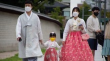 Ein Familie mit Gesichtsmasken und traditioneller Kleidung geht vor dem Gyeongbokgung-Palast in Seoul spazieren. Foto: epa/Jeon Heon-kyun
