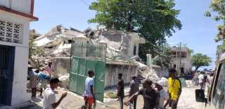Menschen stehen vor der Residenz des katholischen Bischofs, die bei einem Erdbeben beschädigt wurde. Bei einem schweren Erdbeben auf Haiti sind heute mehrere Menschen ums Leben gekommen. Das teilte die Zivilschutzbehörd... Foto: Delot Jean/Ap/dpa