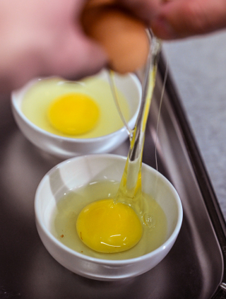 Für das Herstellen von pochierten Eiern werden im Bonvivant Cocktail Bistro Eier in eine Schale gegeben. Foto: Jens Kalaene/dpa