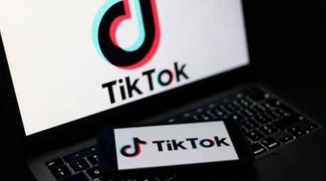 Das Logo der TikTok-Plattform auf einem Smartphone und Laptop. In Großbritannien wird ein mögliches Social-Media-Verbot für unter 16-Jährige diskutiert. Foto: EPA/Adam Vaughan