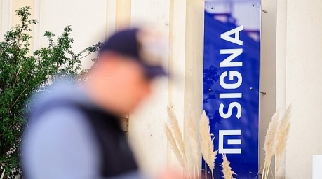 Ein Mann geht an einem Logo des österreichischen Immobilien- und Handelsunternehmens Signa Holding in der Wiener Niederlassung der Gruppe vorbei. Foto: epa/Christian Bruna