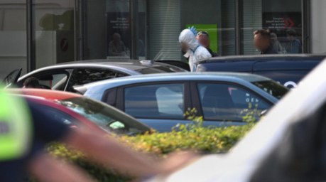 Nach einem tödlichen Messerangriff führt die Polizei in Regensburg eine Person in Schutzkleidung vom Einsatzort an einer Bankfiliale ab. Foto: Armin Weigel/dpa