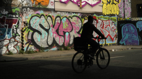 Ein Mann radelt an Graffiti im Londoner Stadtteil Tower Hamlets vorbei. Foto: Alessandra Tarantino/Ap/dpa