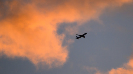 Eine Boeing 737 von TUI fly auf dem Weg von Hannover nach Palma de Mallorca zeichnet sich vor dem vom Sonnenaufgang verfärbten Morgenhimmel ab. Foto: Julian Stratenschulte/dpa