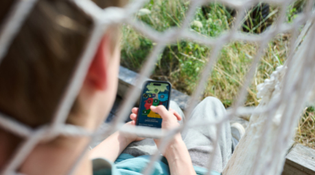 Ein Teenager liegt in einem Hängesessel und guckt auf sein Handy. Foto: Annette Riedl/dpa