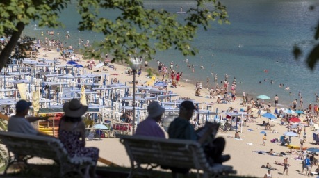 Menschen suchen im Schatten nahe dem Strand La Concha in San Sebastián Schutz vor der anhaltenden Hitzewelle in Spanien. Foto: EPA/Javier Etxezarreta