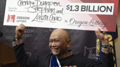 Cheng "Charlie" Saephan hält einen übergroßen Scheck über seinen Kopf, nachdem er auf einer Pressekonferenz in der Lotteriezentrale von Oregon in Salem. Foto: Jenny Kane/Ap/dpa