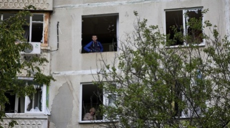 Leute schauen durch zerbrochene Fensterscheiben am Ort eines Beschusses auf ein Wohngebiet in Charkiw. Foto: epa/Sergey Kozlov 52508