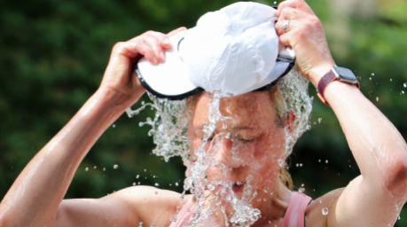 Eine Teilnehmerin des Hamburger Halbmarathons kühlt sich an einer Erfrischungsstation mit Wasser gegen die sommerliche Hitze ab. Foto: dpa/Markus Tischler