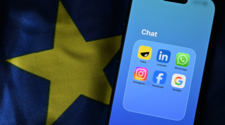 Die Apps Yubo, LinkedIn, WhatsApp, Facebook, Google und Instagram sind auf einem Smartphone zu sehen, das auf einer EU-Flagge liegt. Foto: Markus Lenhardt/dpa