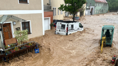 Ein Auto treibt nach starkem Regen in einer Straße im Wasser. Menschen wurden in ihren Häusern eingeschlossen. Foto: Haubner/Vifogra/dpa