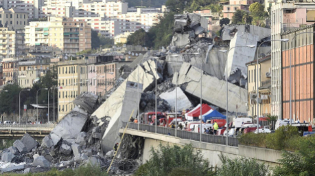 Fahrzeuge der Rettungskräfte stehen vor der teilweise eingestürzten Autobahnbrücke. 2018 kamen beim Einsturz der "Ponte Morandi" auf etwa 100 Metern Länge 43 Menschen ums Leben. Foto: Luca Zennaro/Ansa/ap/dpa