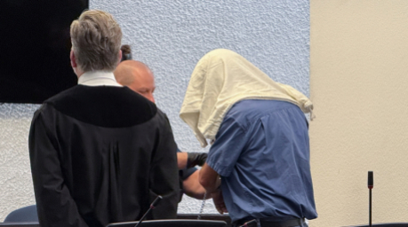 Der angeklagte Kita-Betreiber mit verdecktem Gesicht und seinem Anwalt Bernd Kiefer im Gerichtssaal. Foto: dpa/David Nau