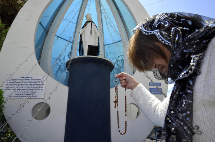 Eine Christin trägt einen Rosenkranz und betet vor der Statue der Jungfrau Maryt. Foto: epa/Wael Hamzeh
