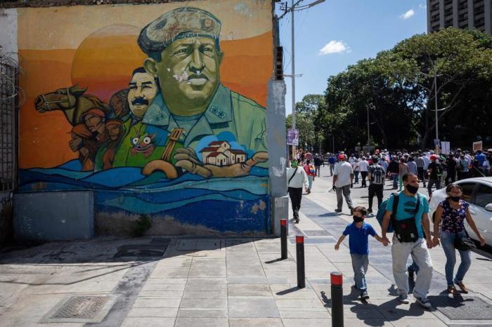 Leute gehen neben einem Wandgemälde des ehemaligen Präsidenten Hugo Chavez und des venezolanischen Präsidenten Nicolas Maduro in Caracas spazieren. Foto: epa/Rayner Pena R