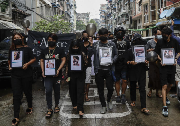 Schwarz gekleidete Demonstranten halten schwarze Luftballons und Bilder der Opfer, die von bewaffneten Truppen erschossen wurden, während sie bei einem Protest gegen den Militärputsch in Yangon marschieren. Foto: epa/Stringer