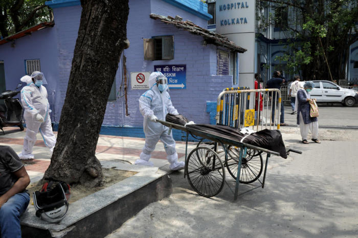 Indischer Gesundheitspersonal hantiert mit der Leiche eines Patienten, der an Covid-19 gestorben ist, im Krankenhaus in Kolkata. Foto: epa/Piyal Adhikary