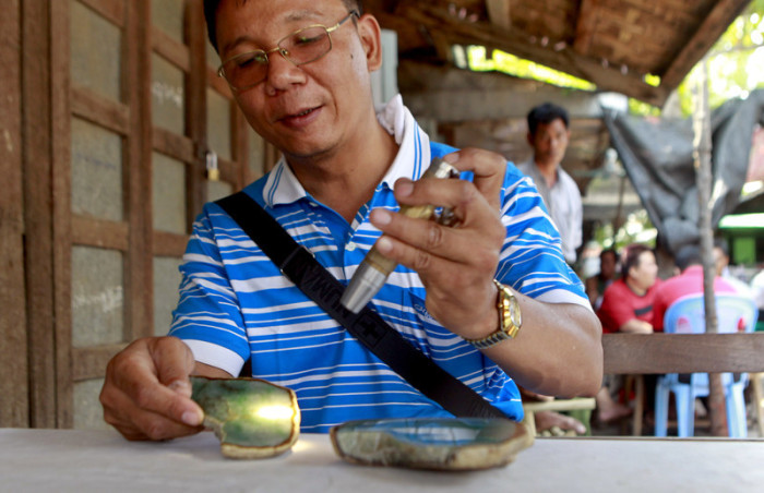 Mit einer Taschenlampe begutachtet ein Händler auf dem Jade-Markt in Mandalay einen der kostbaren Edelsteine. Je besser das Licht durchschimmert, desto höher der Preis. Foto: epa/Pyae Sone Aung