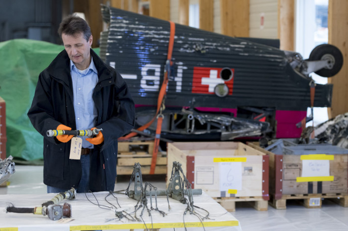 Michael Flueckiger, Chefermittler des Luftfahrtsektors der Schweizerischen Verkehrssicherheitsuntersuchungsstelle STSB, untersucht Teile des Wracks des Flugzeugs Junkers JU-52, HB-HOT, im STSB-Gebäude in Payerne. Foto: epa/Laurent Gillieron