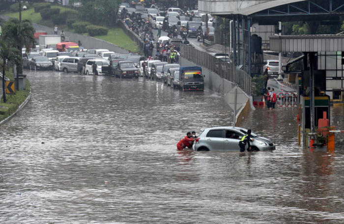 Ein indonesischer Bürger schiebt ein Auto durch das Hochwasser auf einer Autobahn in Jakarta. Foto: epa/Bagus Indahono