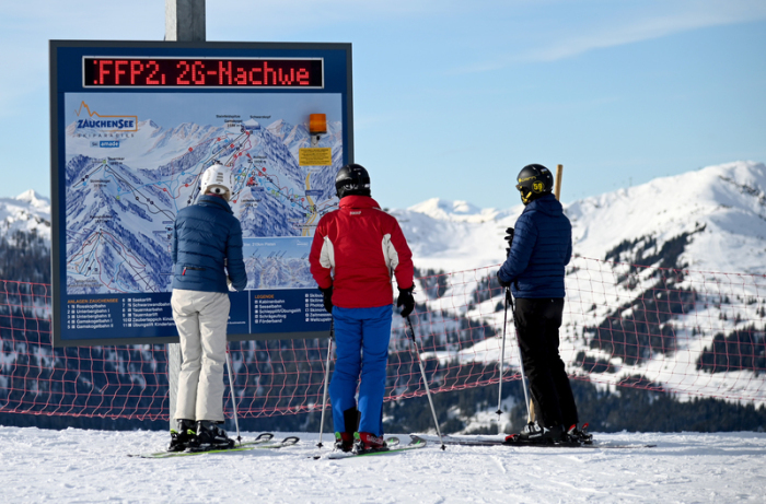kifahrer stehen vor einer Informationstafel mit der Aufforderung nach FFP2-Masken und 2G-Nachweis im Skigebiet Altenmarkt-Zauchensee. Foto: Barbara Gindl/dpa