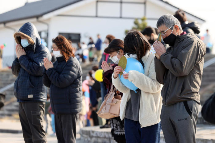 Leute beobachten einen Moment des stillen Gebets für die Opfer des verheerenden Erdbebens und Tsunamis 2011 in Soma. Foto: epa/Jiji Press