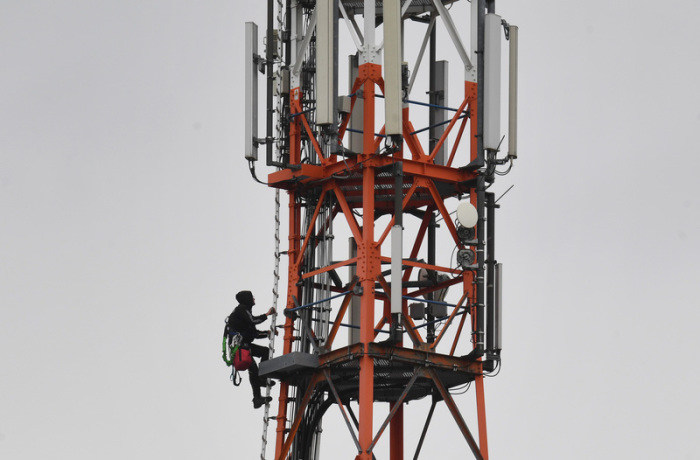 Ein Techniker klettert an einem Funkmast neben Mobilfunkantennen für den Mobilfunkstandard 5G.. Foto: Stefan Sauer/Zb/dpa