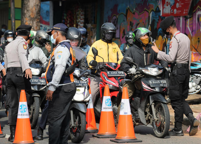 Indonesische Polizeibeamte kontrollieren Autofahrer an einem Kontrollpunkt, um die Verhängung der COVID-19 Notfallbeschränkungen in Jakarta durchzusetzen. Foto: epa/Bagus Indahono