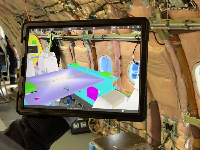 Ein Mitarbeiter schaut sich in einem noch leeren Flugzeugrumpf auf einem Tablet virtuell die 3D-Konstruktionsdaten der geplanten Kabineneinrichtung an. Foto: Jan Brandes/Lufthansa Technik Ag/dpa