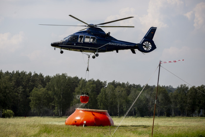 Ein Hubschrauber der Bundespolizei nimmt in Frankenförde Löschwasser auf. Foto: Christoph Soeder/Dpa