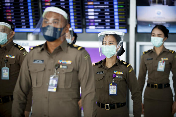 Thailändische Einwanderungsbeamte tragen Schutzmasken und Visiere während ihrer Schicht am internationalen Flughafen Suvarnabhumi in Bangkok. Foto: epa/Diego Azubel