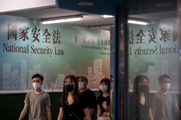 Leute gehen an einer Plakatwand mit einer Anzeige für das Gesetz zur nationalen Sicherheit in Hongkong vorbei. Foto: epa/Jerome Favre