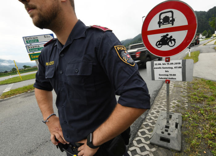 Ein Polizist steht vor einem Schild, das auf die Sperrung für den Verkehr mit Fahrziel Italien hinweißt. Foto: Angelika Warmuth/Dpa