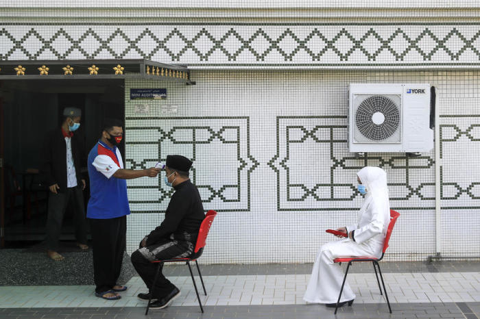 Ein Beamter der Islamischen Religionsabteilung Malakka (2-L) überprüft die Temperatur von Personen an einer Hochzeitszeremonie. Foto: epa/Fazry Ismail