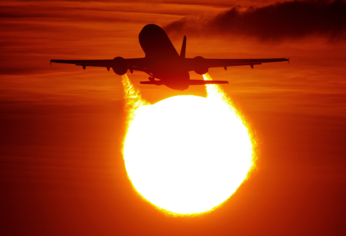 Ein Flugzeug startet am Flughafen in Düsseldorf vor der Sonne. Foto: Julian Stratenschulte/Dpa
