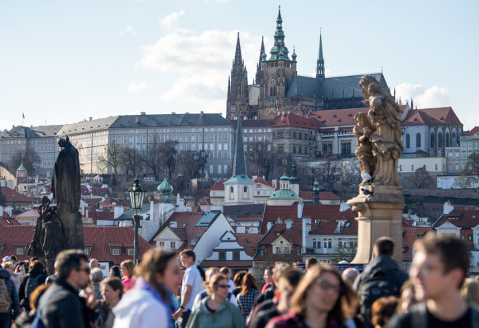 Zahlreiche Touristen gehen über die Karlsbrücke. Im Hintergrund ist die Prager Burg zu sehen. Foto: Monika Skolimowska/Zb/dpa