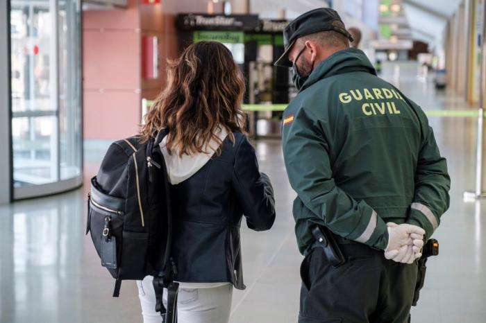 Ein spanischer Guardia Civil spricht mit einem Passagier auf dem Flughafen von Ibiza, Balearen. Foto: epa/Sergio G. Cañizares